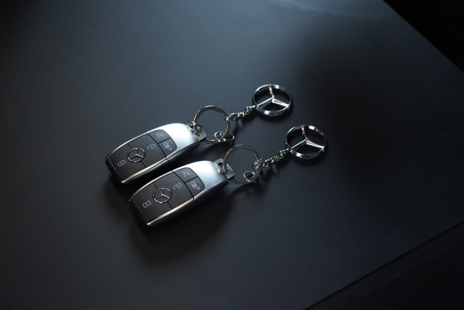 Two Mercedes-Benz keys on a graphite surface